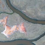 Stunning aerial shot of salt ponds creating abstract, colorful patterns in a natural landscape.